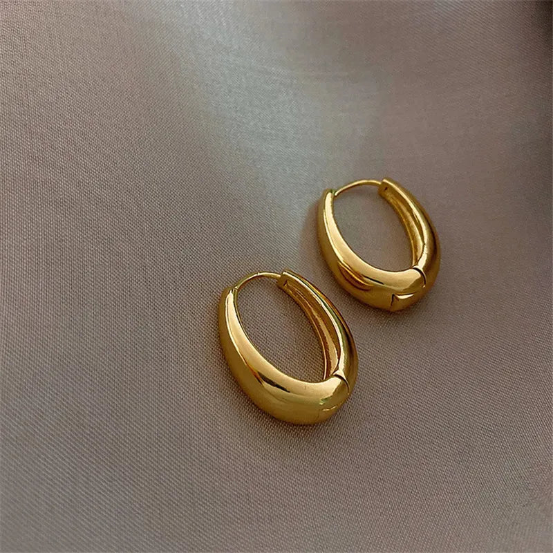 Vintage hoop drop earrings featuring classic gold-toned hoops with intricate detailing, stylishly displayed on a neutral background.