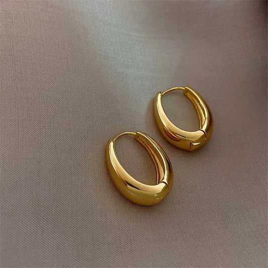 Vintage hoop drop earrings featuring classic gold-toned hoops with intricate detailing, stylishly displayed on a neutral background.