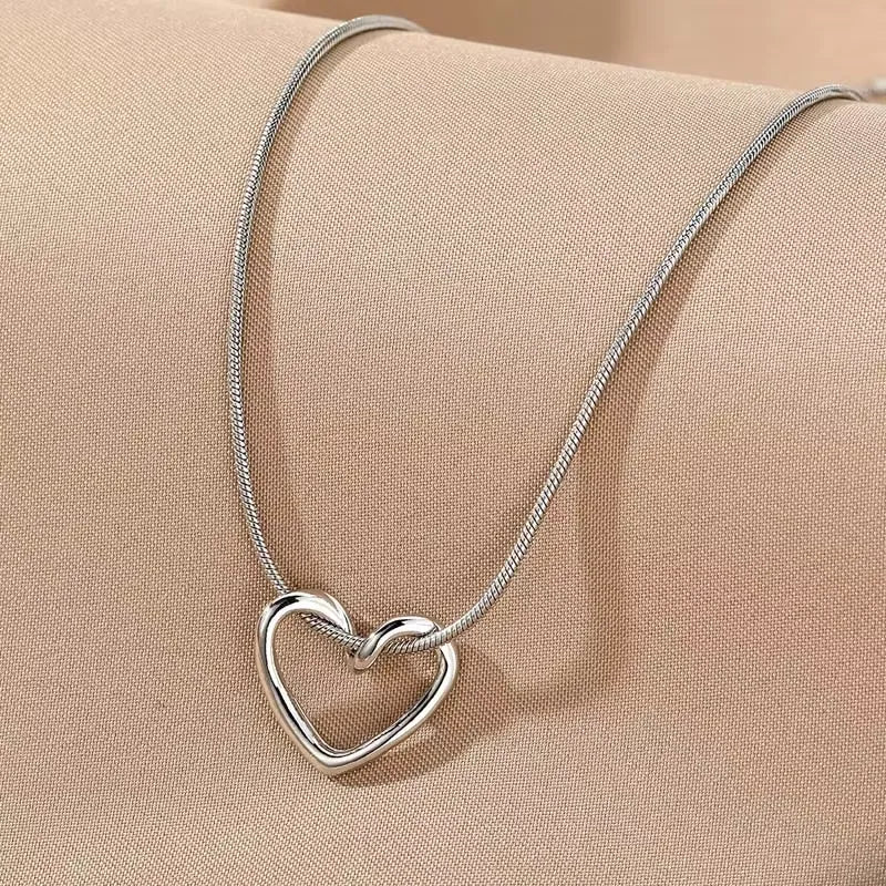 Silver heart pendant necklace with a delicate chain, featuring a shiny, polished heart-shaped charm, stylish accessory for women.